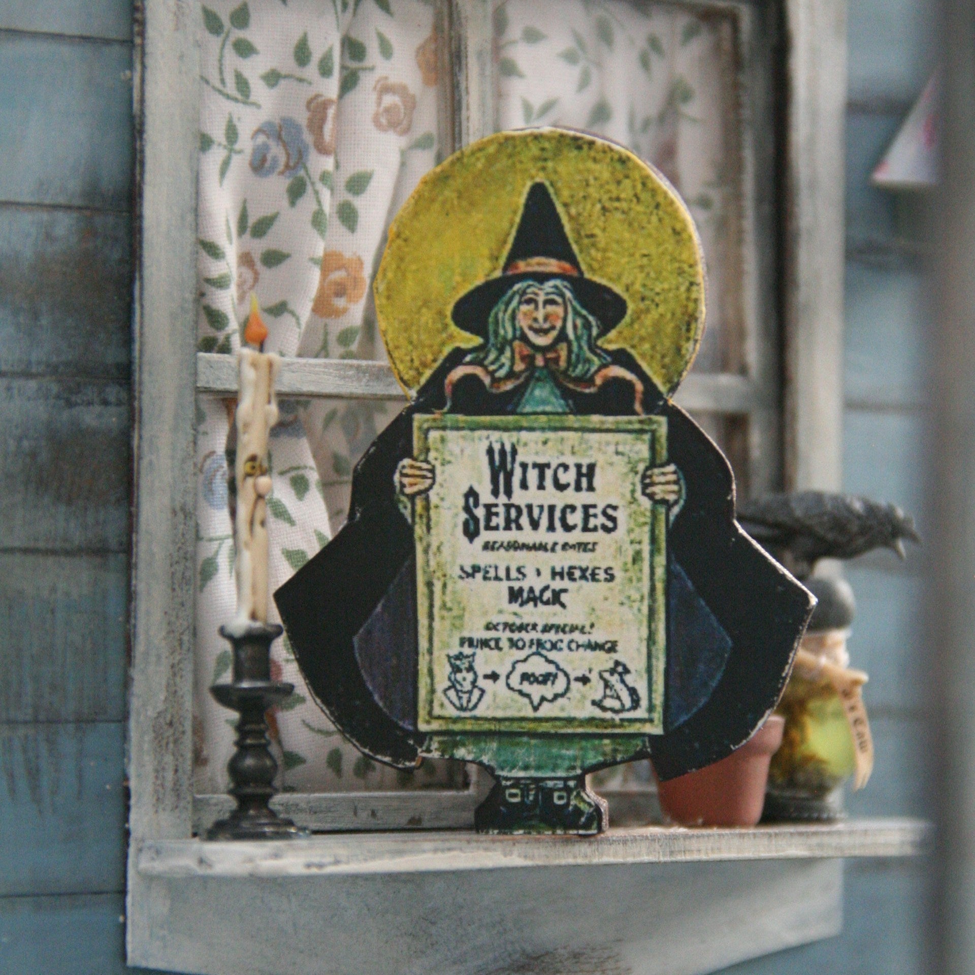 Witch-themed decor with a framed picture of a witch holding a sign labeled 'Witch Services' on a shelf.